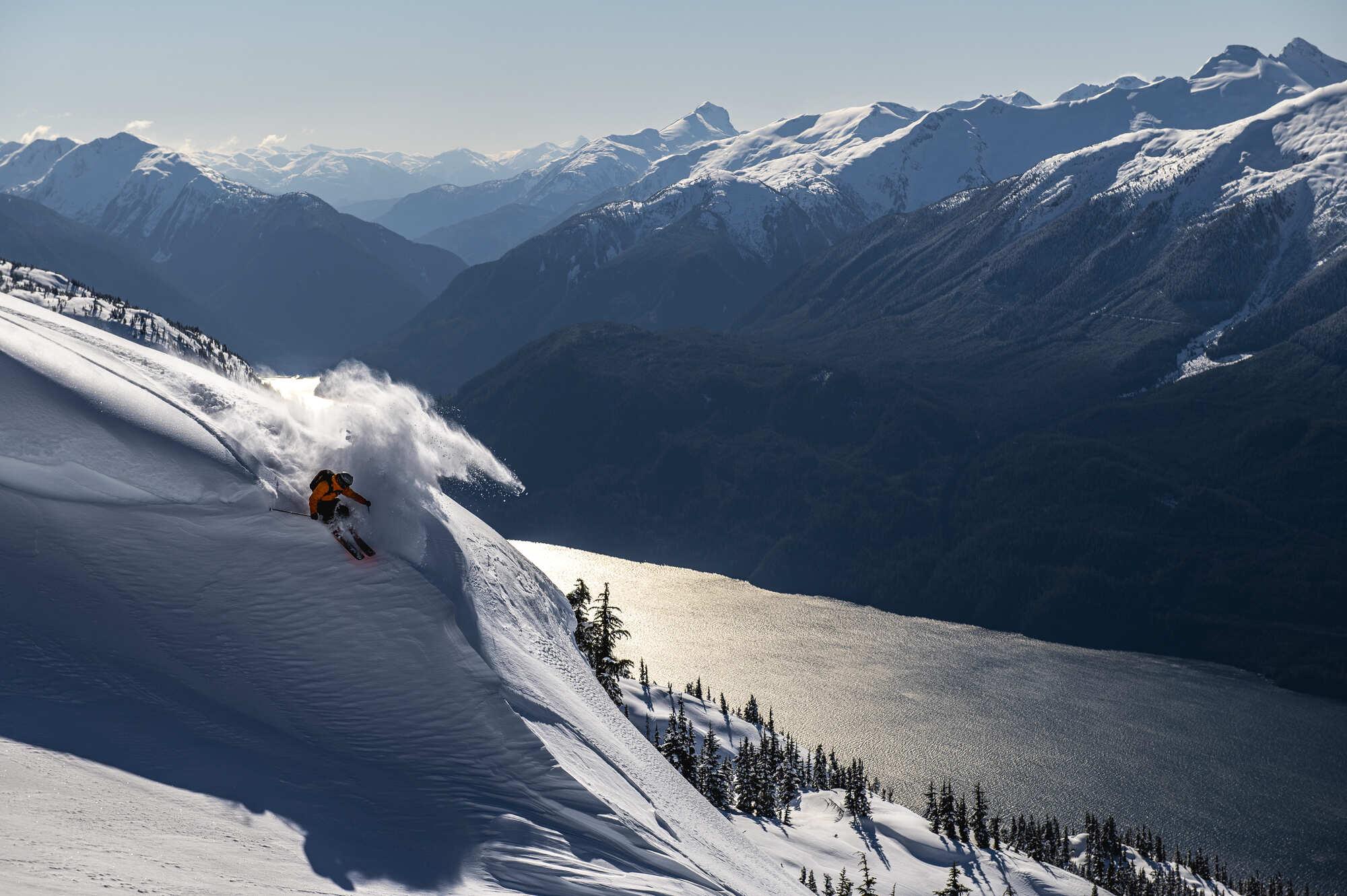 person in an orange jacket skiing down a mountain