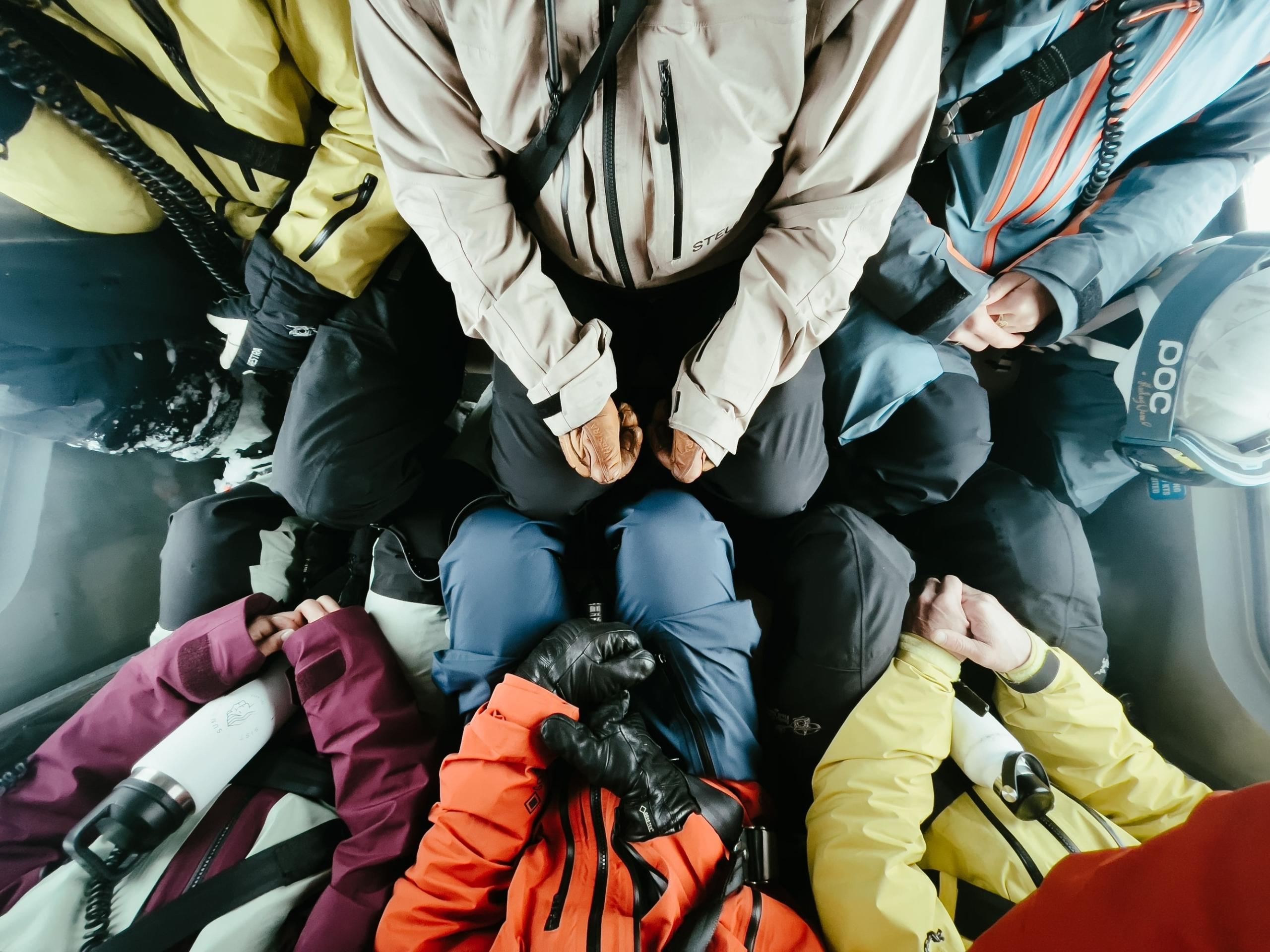 a group of six skiers sitting in a helicopter