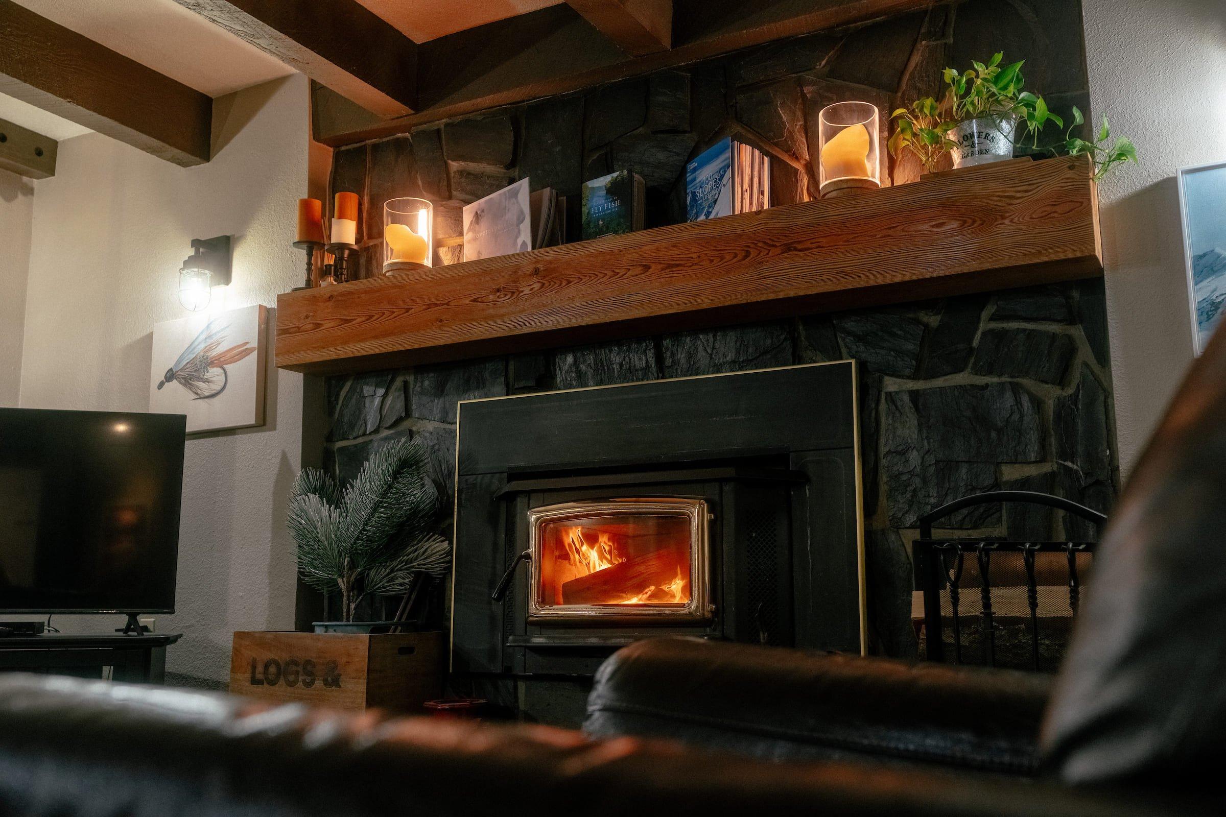The living room of a wilderness lodge with a wood burning fireplace and a hard wood mantle